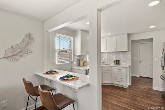 kitchen featuring tasteful backsplash, light stone counters, white cabinets, and dark wood finished floors