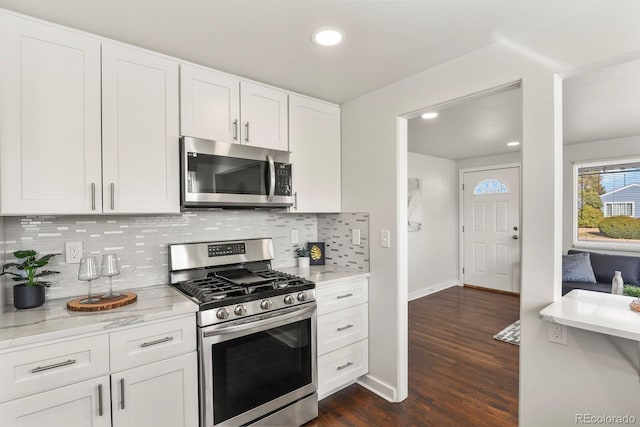 kitchen featuring stainless steel appliances, dark wood-style flooring, white cabinets, and light stone counters