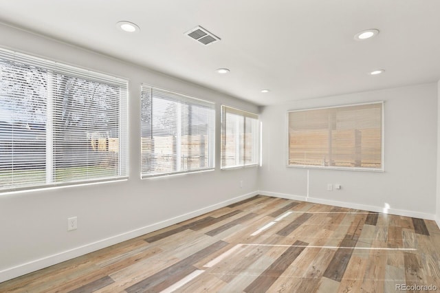 unfurnished room with recessed lighting, wood finished floors, visible vents, and baseboards