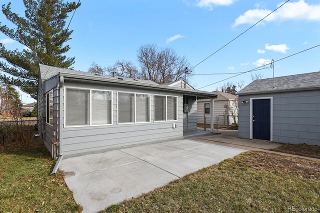 exterior space with a shingled roof and a patio area