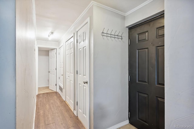 corridor with ornamental molding and light wood-type flooring