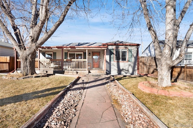 ranch-style home featuring a porch, a front lawn, and fence