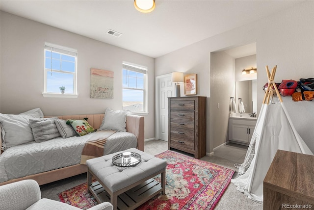 interior space featuring light colored carpet, ensuite bath, baseboards, and visible vents