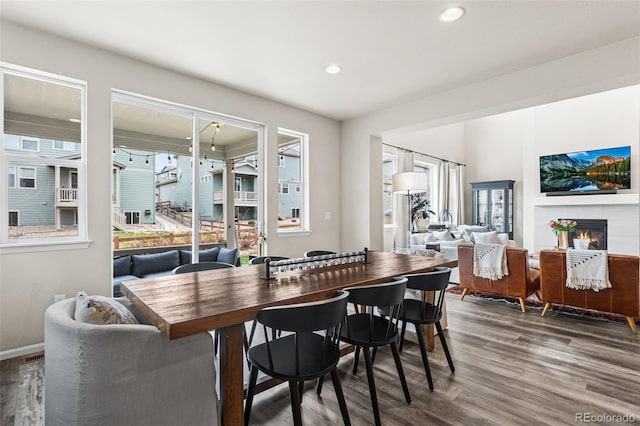 dining area featuring baseboards, a glass covered fireplace, recessed lighting, and wood finished floors