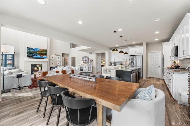 dining area with visible vents, wood finished floors, a glass covered fireplace, and recessed lighting