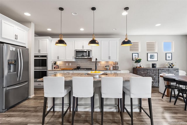 kitchen with stainless steel appliances, white cabinetry, backsplash, and dark wood finished floors