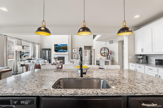 kitchen with dishwashing machine, an island with sink, a sink, open floor plan, and visible vents