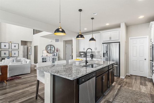 kitchen featuring a sink, a center island with sink, white cabinetry, appliances with stainless steel finishes, and dark wood-style floors