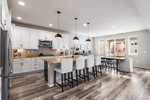 kitchen with white cabinetry, dark wood-style flooring, appliances with stainless steel finishes, and a breakfast bar