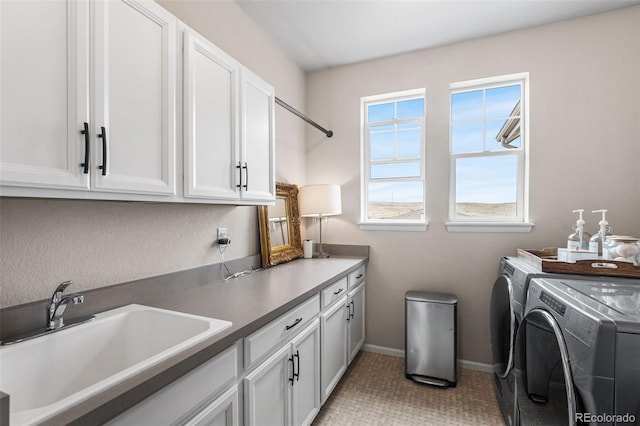 washroom featuring cabinet space, washing machine and clothes dryer, baseboards, and a sink