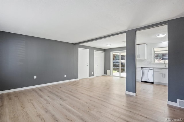 unfurnished living room with light hardwood / wood-style flooring and sink