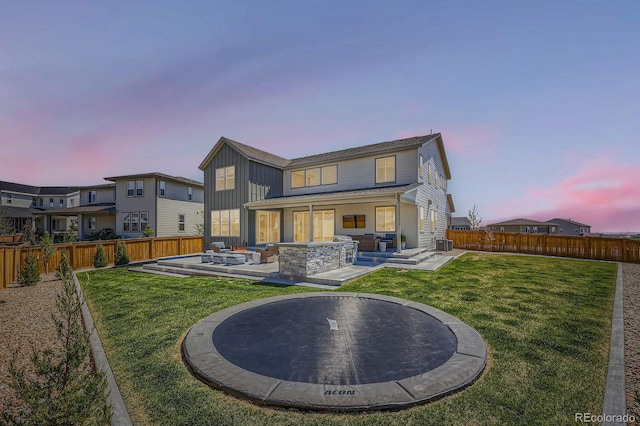 back of house at dusk featuring a patio area, board and batten siding, and central air condition unit