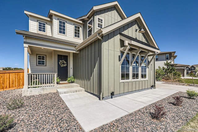 view of front of house featuring board and batten siding, fence, and covered porch