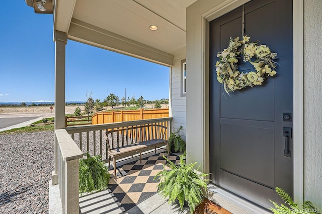 view of exterior entry with a porch and fence