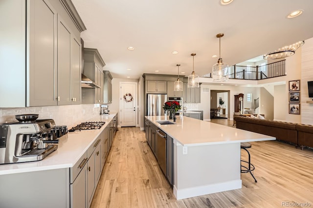 kitchen featuring gray cabinetry, a sink, light wood finished floors, appliances with stainless steel finishes, and light countertops