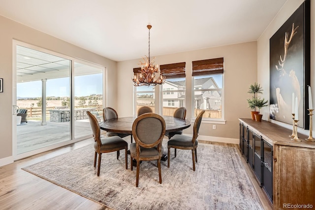 dining room with a chandelier, light wood finished floors, and baseboards