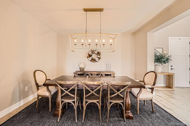 dining space featuring wood finished floors, baseboards, and a chandelier