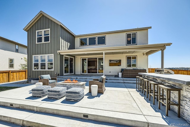 rear view of house with a fire pit, a patio area, fence, and board and batten siding