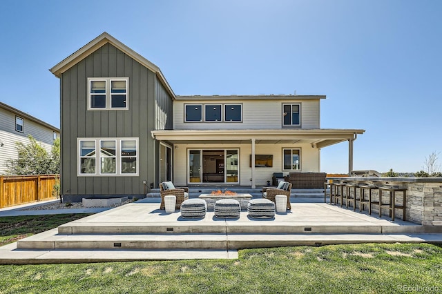 back of property featuring an outdoor fire pit, fence, a patio area, and board and batten siding