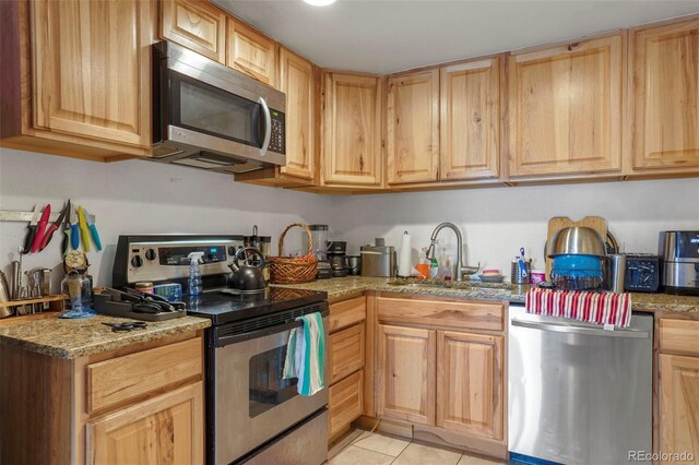 2087 S Grant St, Denver, CO 80210 - kitchen featuring light tile patterned floors, light stone countertops, stainless steel appliances, a sink, and light brown cabinetry