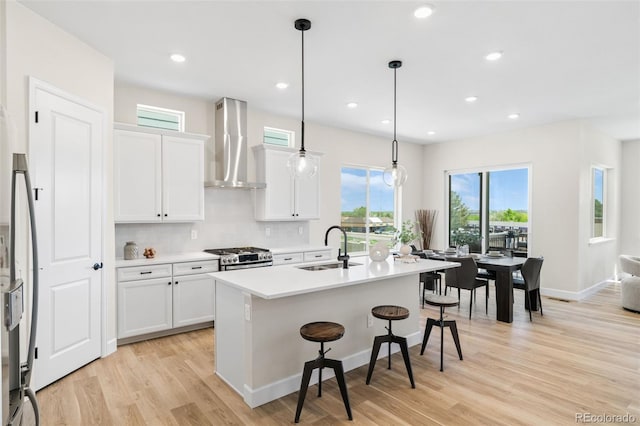 5970 S Platte Canyon Dr, Littleton, CO 80123 - kitchen with wall chimney range hood, a sink, a breakfast bar, a center island with sink, and stainless steel appliances