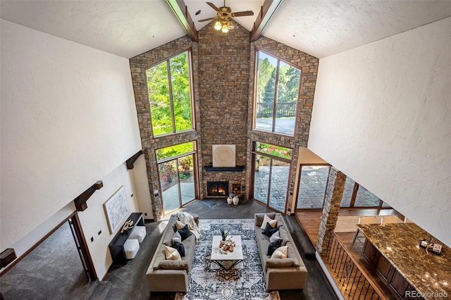 12570 W 60th Ave, Arvada, CO 80004 - carpeted living room featuring a fireplace, beamed ceiling, high vaulted ceiling, ceiling fan, and a textured wall