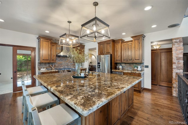 12570 W 60th Ave, Arvada, CO 80004 - kitchen with stainless steel fridge with ice dispenser, brown cabinetry, decorative backsplash, dark stone countertops, and recessed lighting