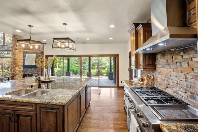 12570 W 60th Ave, Arvada, CO 80004 - kitchen featuring wall chimney range hood, a sink, recessed lighting, wood finished floors, and pendant lighting
