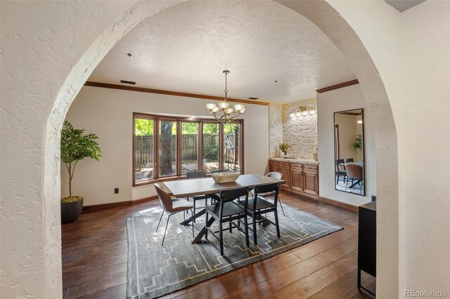 12570 W 60th Ave, Arvada, CO 80004 - dining space featuring dark wood-style floors, crown molding, a chandelier, baseboards, and arched walkways