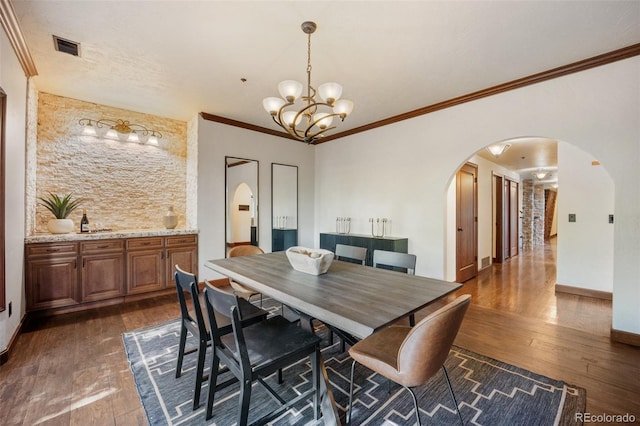 12570 W 60th Ave, Arvada, CO 80004 - dining space featuring arched walkways, dark wood finished floors, a chandelier, ornamental molding, and baseboards