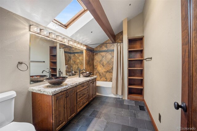 12570 W 60th Ave, Arvada, CO 80004 - bathroom featuring a skylight, double vanity, toilet, stone finish floors, and lofted ceiling