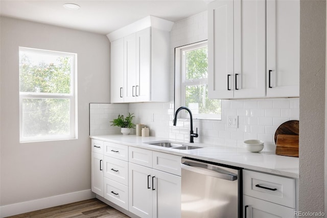 kitchen with sink, backsplash, light hardwood / wood-style floors, stainless steel dishwasher, and light stone countertops