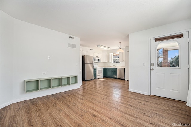 unfurnished living room with sink and light hardwood / wood-style floors