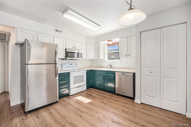 kitchen featuring white cabinetry, decorative light fixtures, stainless steel appliances, and light wood-type flooring