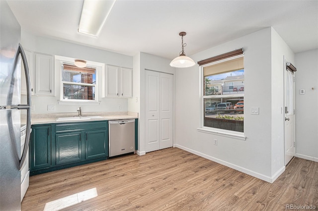 kitchen featuring appliances with stainless steel finishes, sink, light wood-type flooring, and pendant lighting