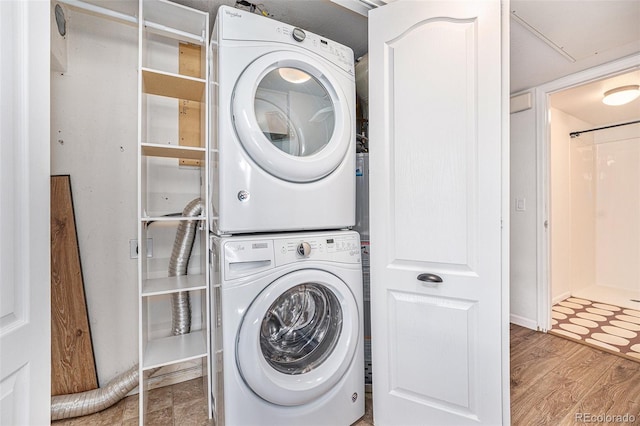 laundry area featuring stacked washing maching and dryer and hardwood / wood-style floors