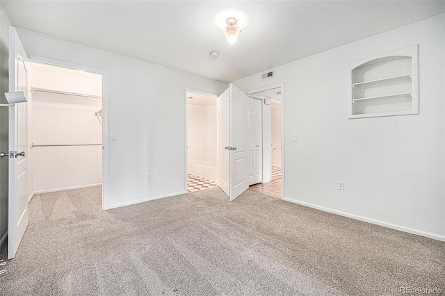 unfurnished bedroom with light carpet, a closet, and a spacious closet