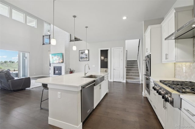 8803 Antero Ct, Arvada, CO 80007 - kitchen with appliances with stainless steel finishes, wall chimney range hood, open floor plan, a sink, and a breakfast bar area