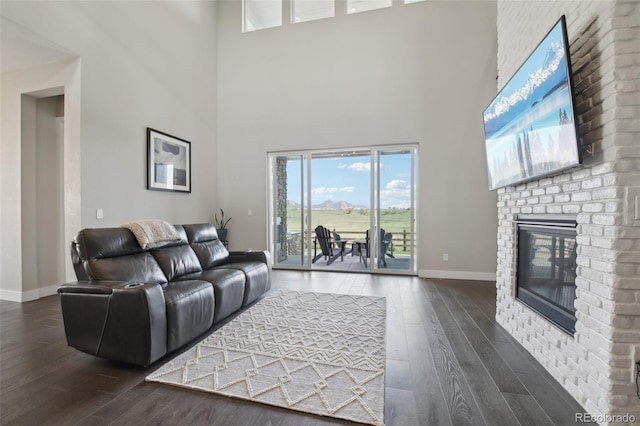 8803 Antero Ct, Arvada, CO 80007 - living room featuring dark wood-style flooring, baseboards, a brick fireplace, and a towering ceiling
