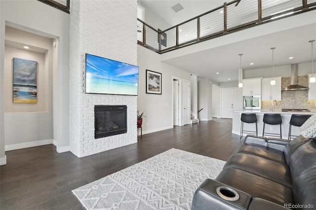 8803 Antero Ct, Arvada, CO 80007 - living room with dark wood-style floors, baseboards, a towering ceiling, a fireplace, and recessed lighting