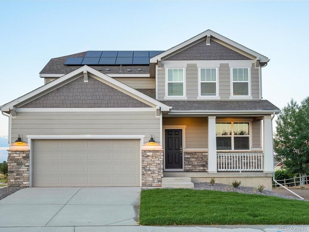 craftsman inspired home with covered porch, solar panels, and a garage