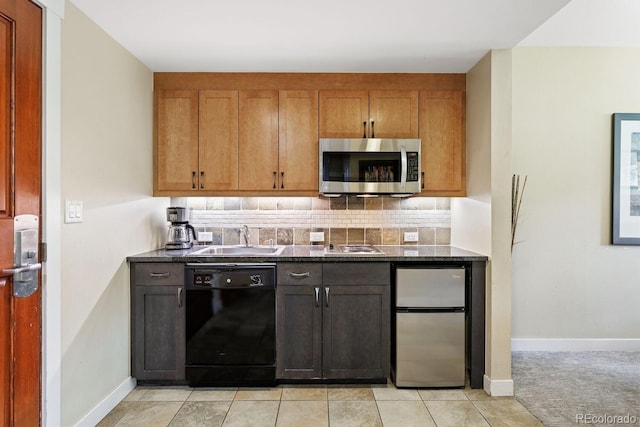 kitchen with decorative backsplash, refrigerator, dark stone counters, sink, and black dishwasher