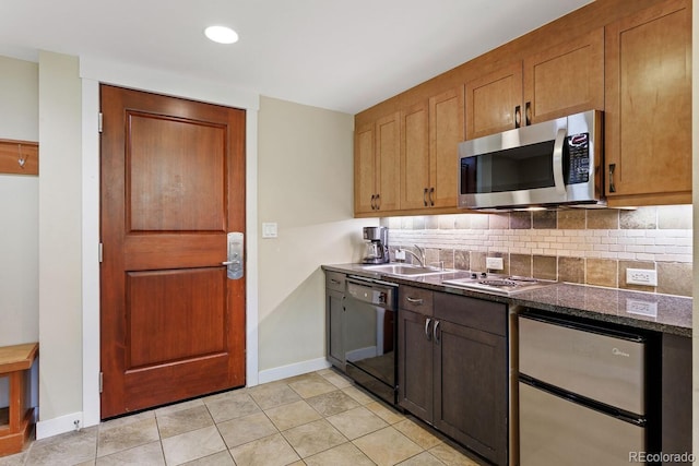 kitchen with dark stone counters, sink, decorative backsplash, light tile patterned floors, and stainless steel appliances