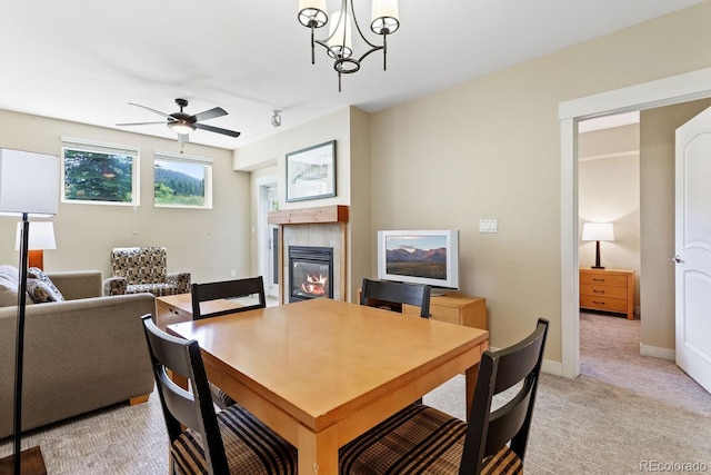 dining space with light carpet and ceiling fan with notable chandelier