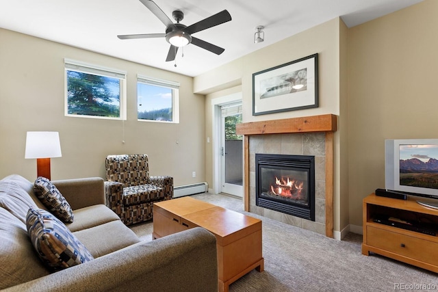 carpeted living room featuring ceiling fan, a baseboard heating unit, and a tiled fireplace