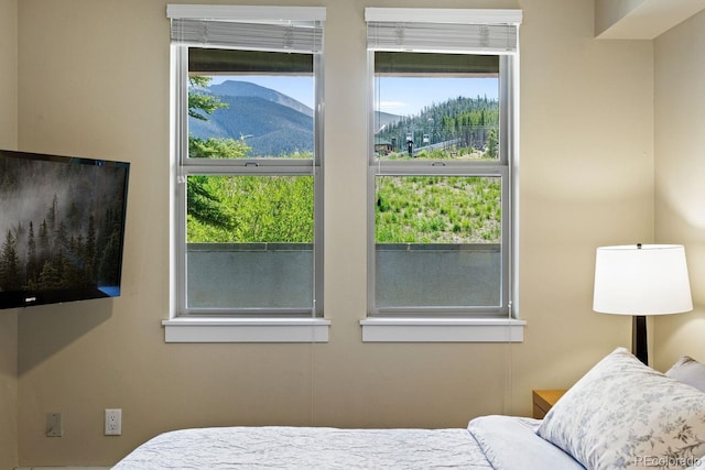 bedroom with a mountain view and multiple windows