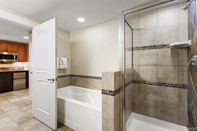 bathroom with separate shower and tub, tile patterned flooring, and a textured ceiling