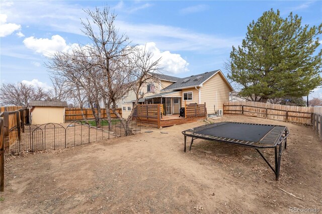 12119 Forest St, Thornton, CO 80241 - back of property featuring a trampoline, a fenced backyard, and a wooden deck