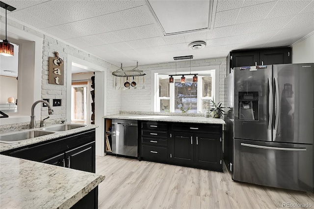 kitchen with appliances with stainless steel finishes, dark cabinetry, and a sink