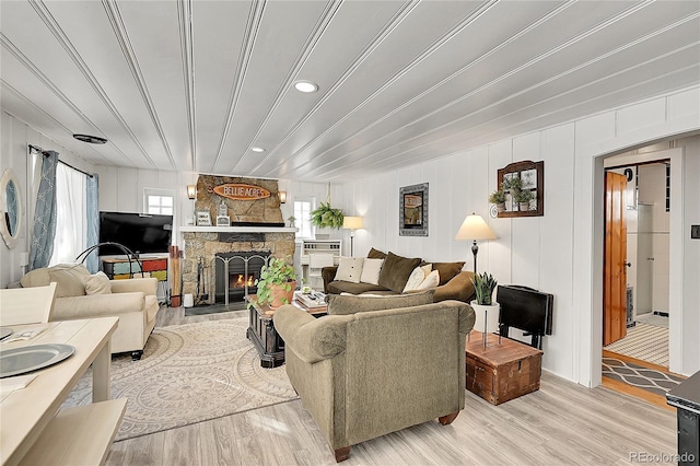 living room featuring light wood-style flooring and a stone fireplace